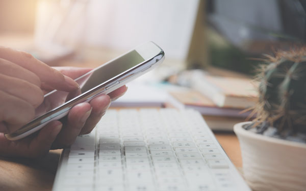 Person mit Smartphone und Tastatur